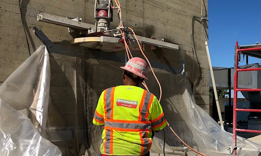 Penhall team using cement saw to cut open new emergency exit door